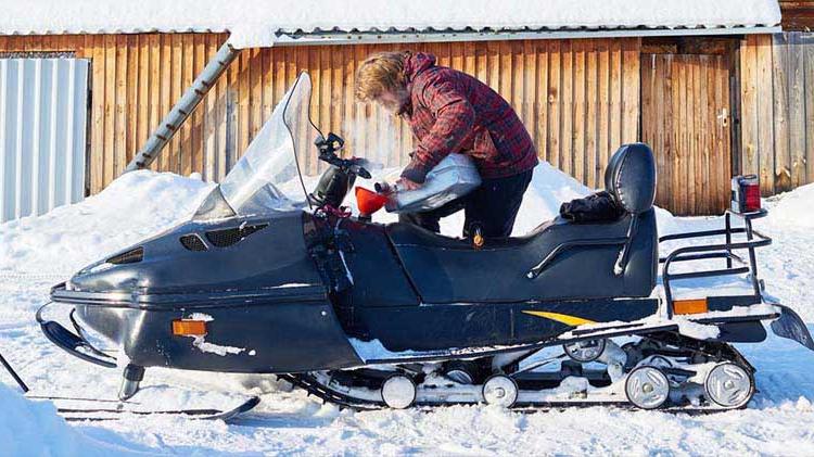 冬天在户外给雪地车加油的人.